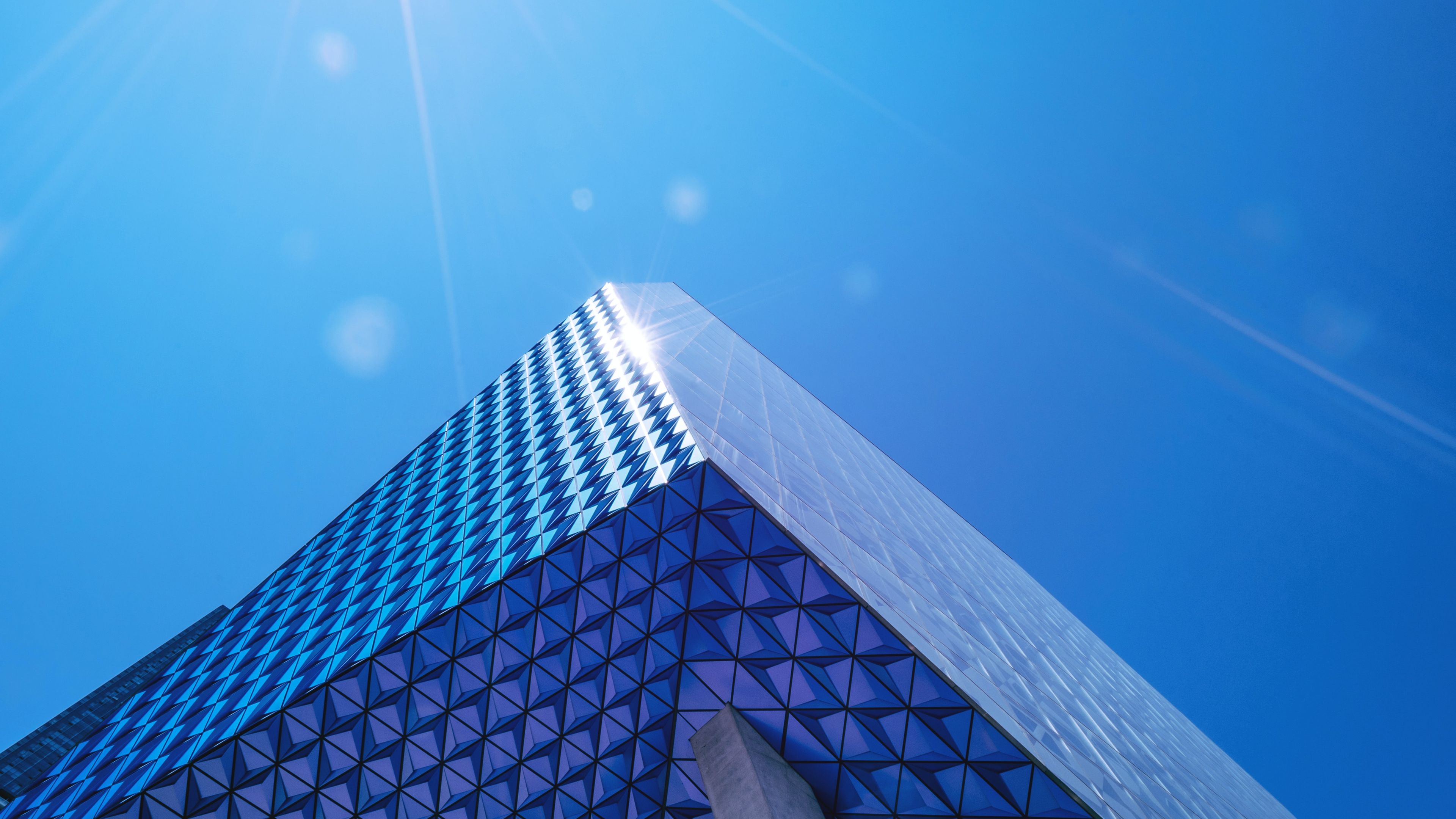 A high rise buiding which glass reflects the blue of a clear sky.